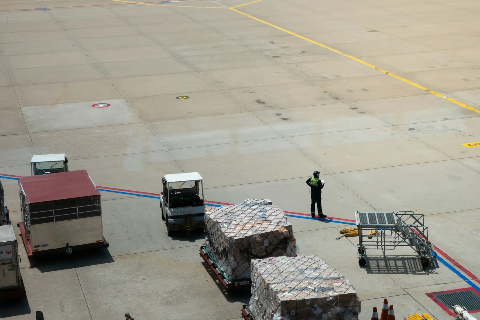 Cargo pallets on dollies being towed across the apron
