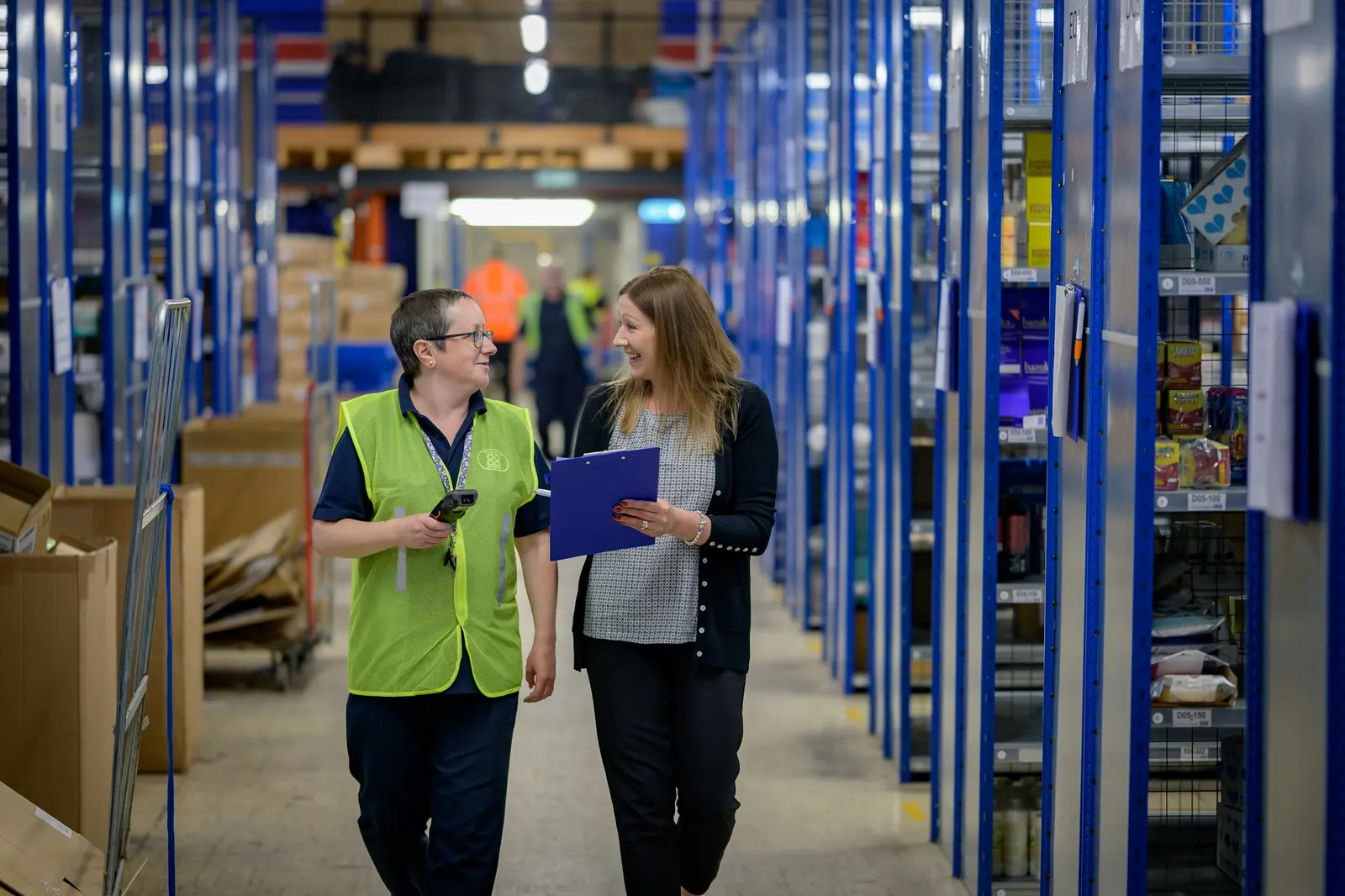 Warehouse staff checking records in an aisle